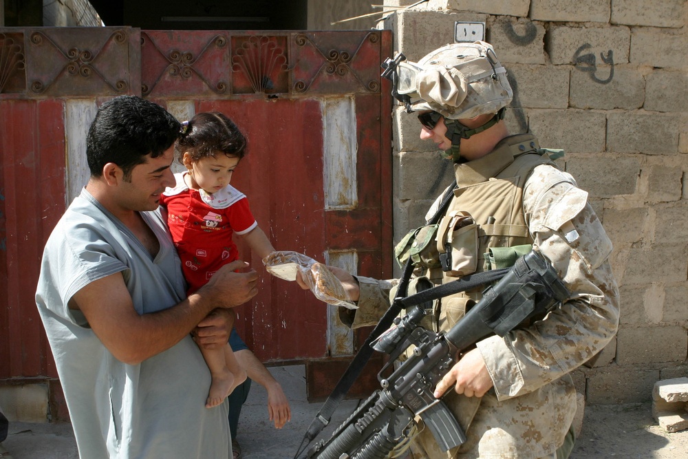 Marine Lance Cpl. Matthew Fordham offers a Iraqi child a package of cookies.