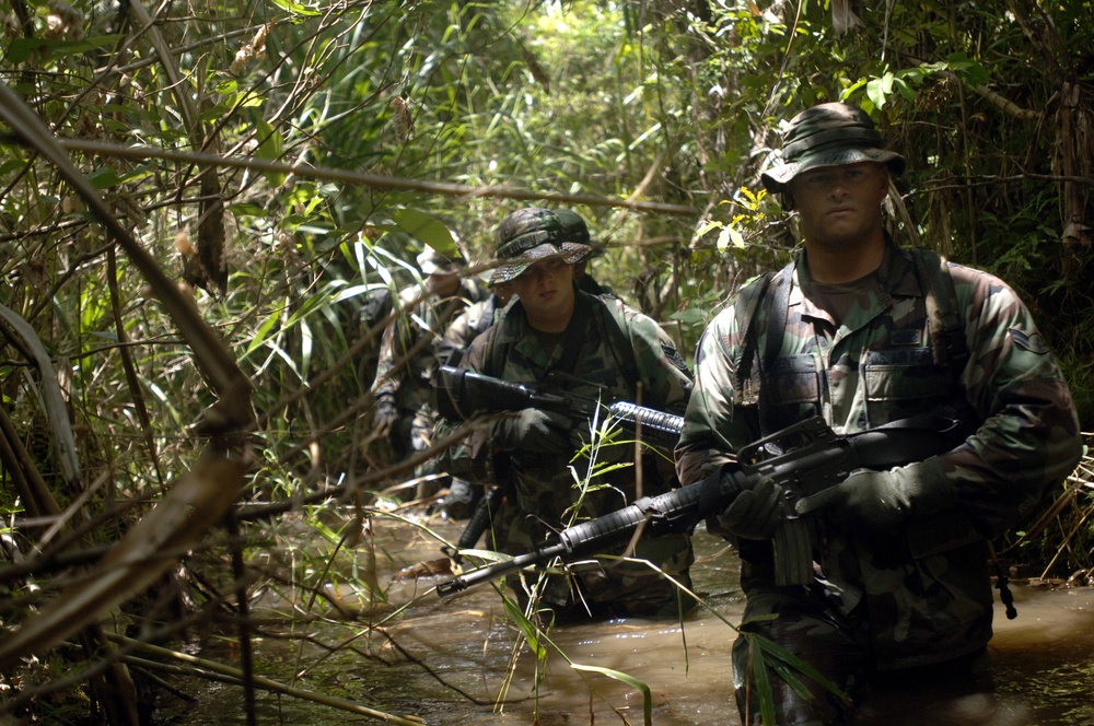 U.S. Air Force Airman 1st Class Dennis Nugent wades through water in the jungles of southern Guam.