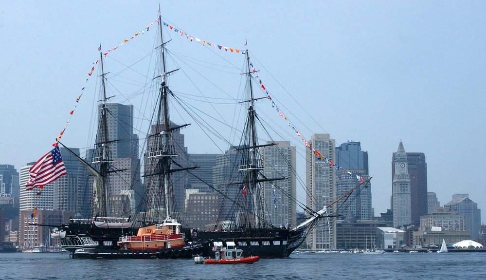 Tugs and U.S. Coast Guard boats escort the USS Constitution to Castle Hill Island.