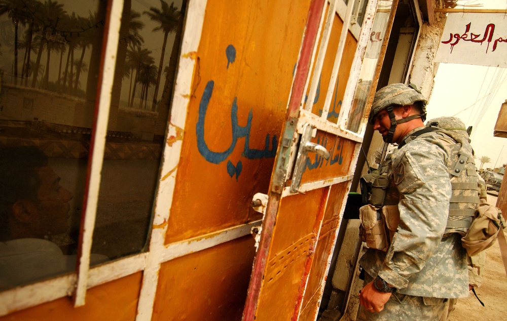 Army Lt. Roy Miller ducks his head into a shop as he conducts an information operation.