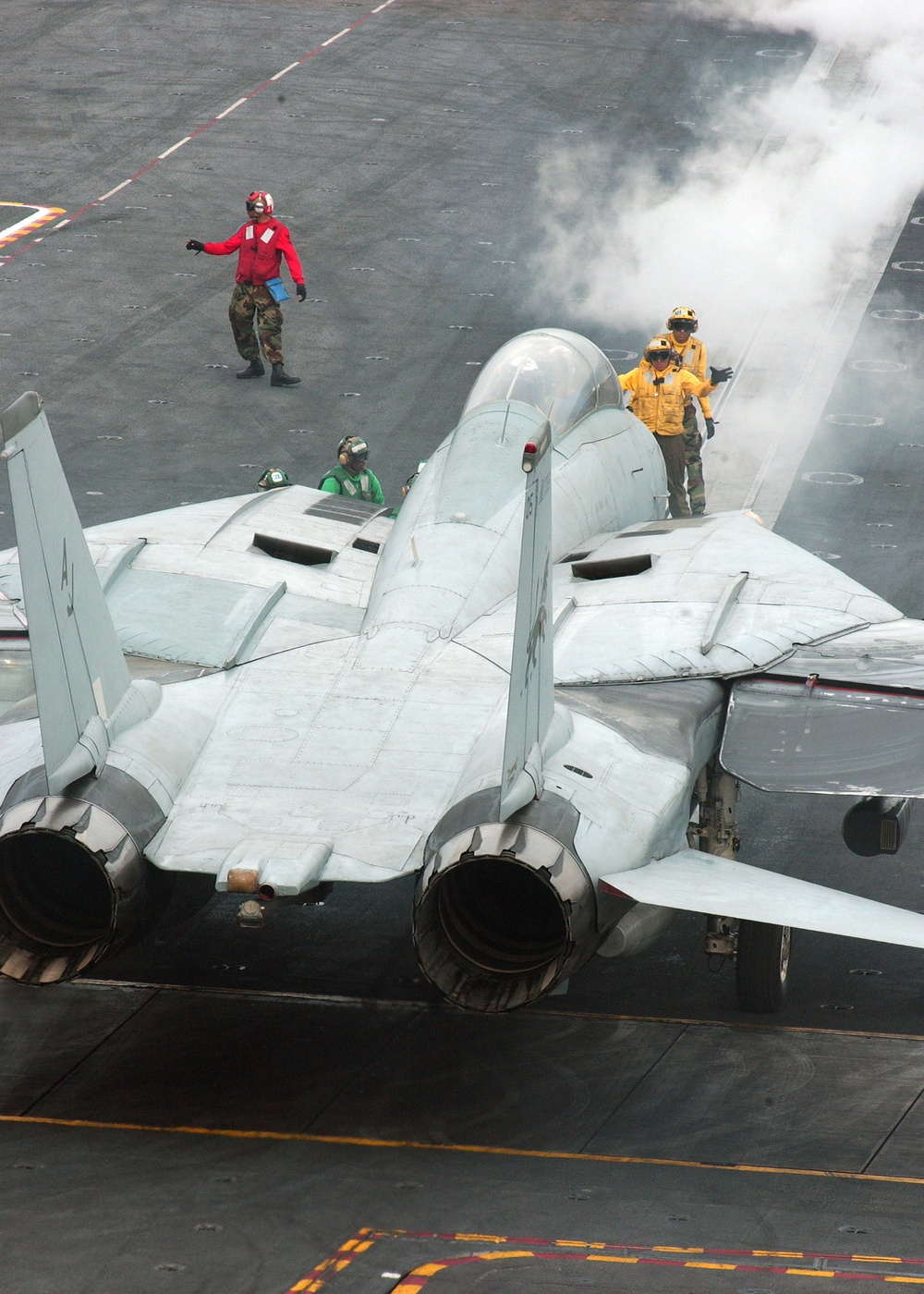 A Navy F-14D Tomcat is being directed to the catapult for launch.