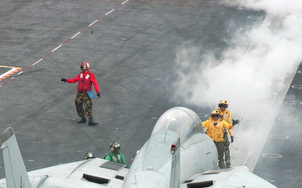 A Navy F-14D Tomcat is being directed to the catapult for launch.
