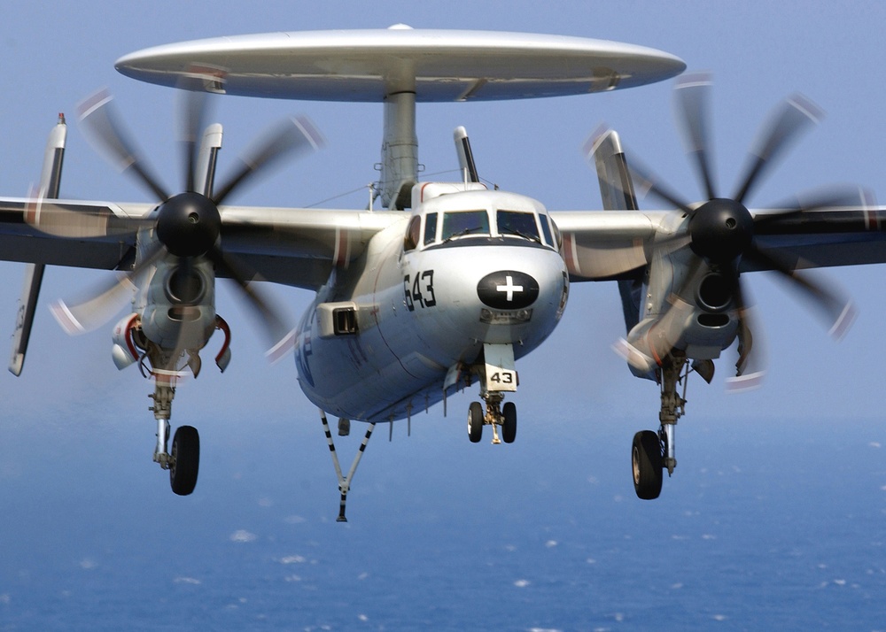 A Navy E-2C Hawkeye approaches for an arrested landing on the flight deck.