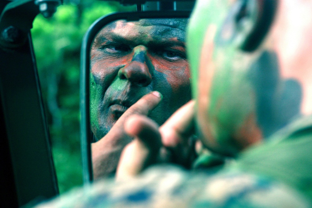 U.S. Marine Staff Sgt. Michael G. Walker applies camouflage face paint.