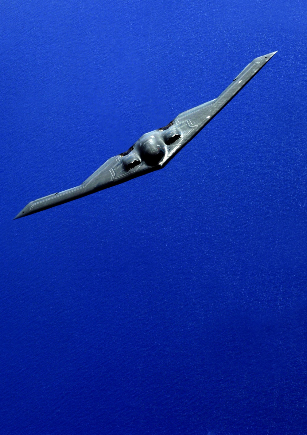 An Air Force B-2 Spirit bomber banks as it maneuvers into position for aerial refueling.