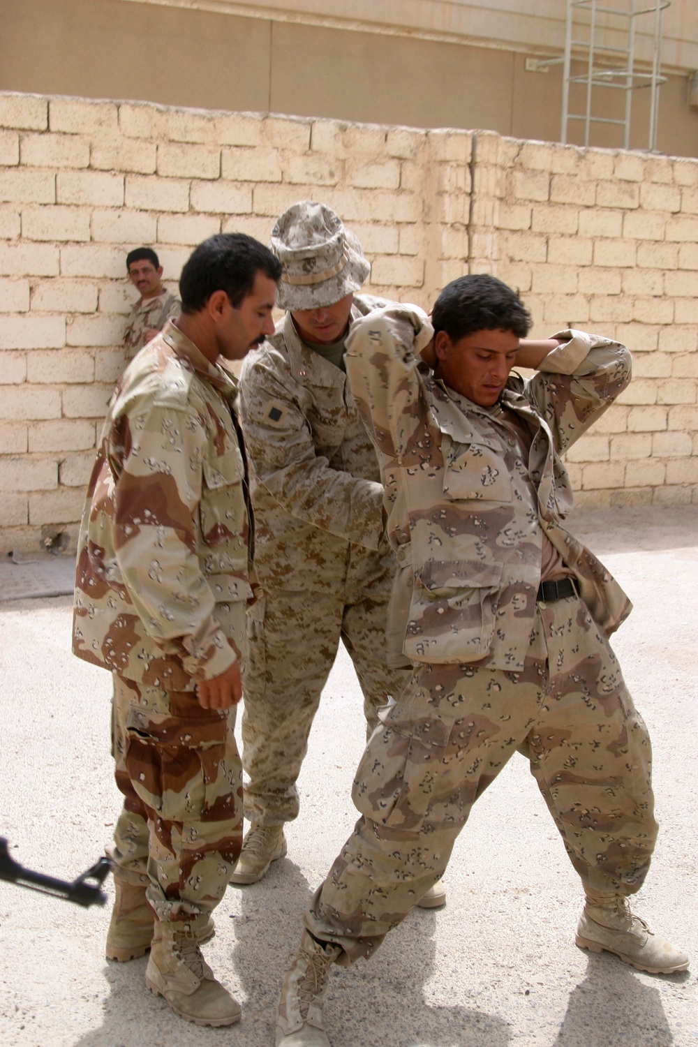 Marine Chief Warrant Officer Kenneth Silvers shows an Iraqi Security Force soldier how to take down an uncooperative detainee.