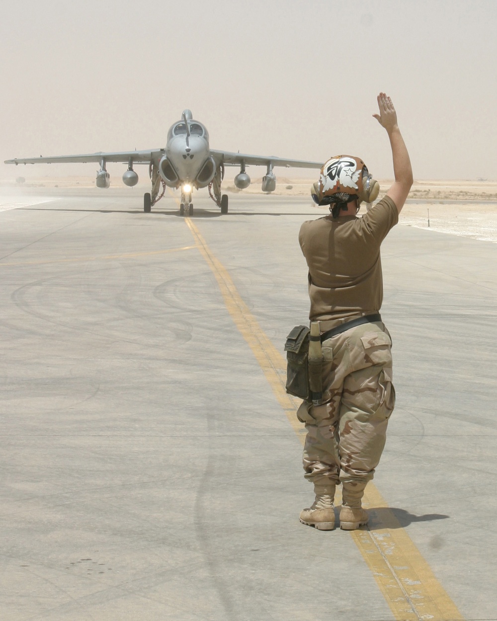 Navy Airman Broquel Schaefer signals the pilot of a Navy EA-6B Prowler.
