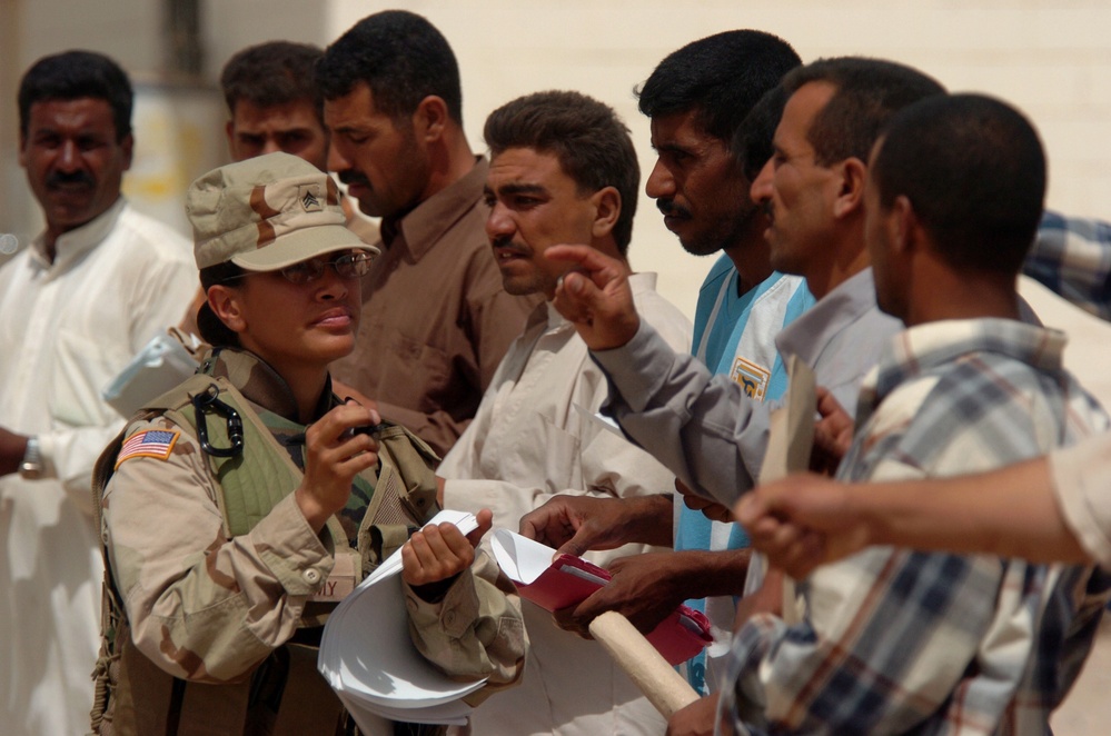 U.S. Army Sgt. Amber Aki helps Iraqi men.