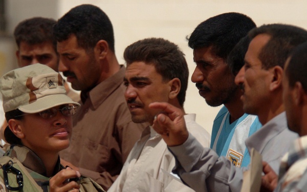U.S. Army Sgt. Amber Aki helps Iraqi men.