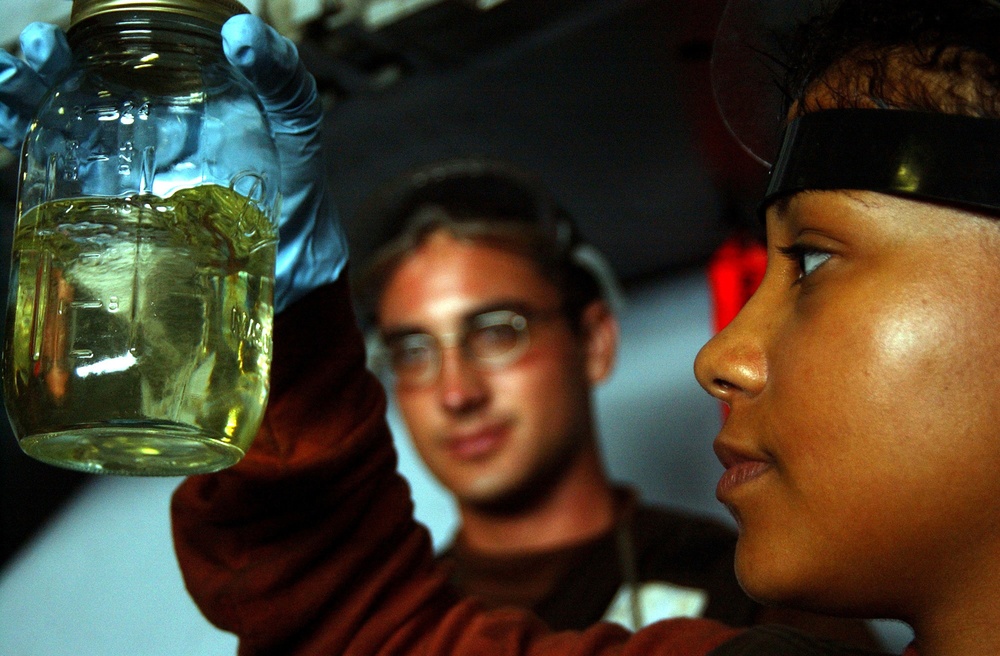Navy Airman Malerie Love inspects a sample of JP5 jet fuel.