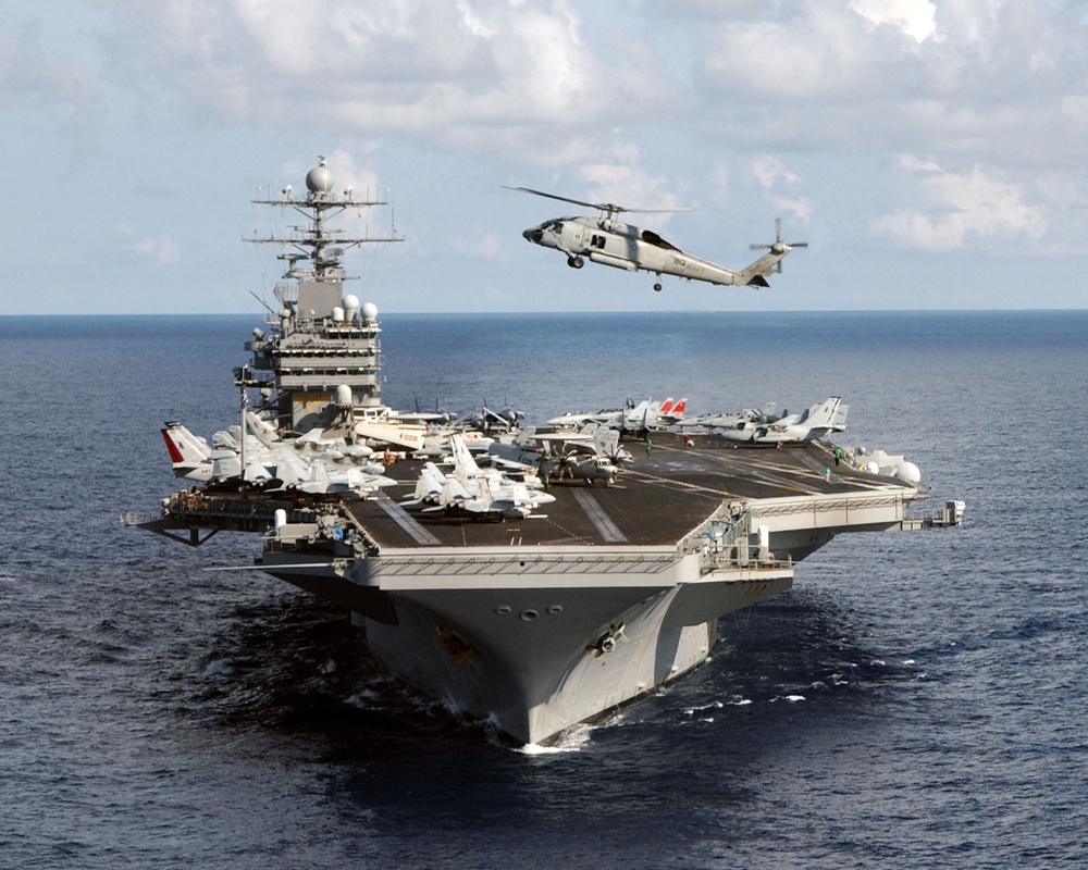 A Navy SH-60 Seahawk helicopter flies over the bow of the aircraft carrier USS Theodore Roosevelt.