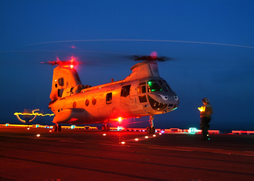 A U.S. Navy Landing Signal Enlisted prepares a CH-46 Sea Knight helicopter for lift-off.