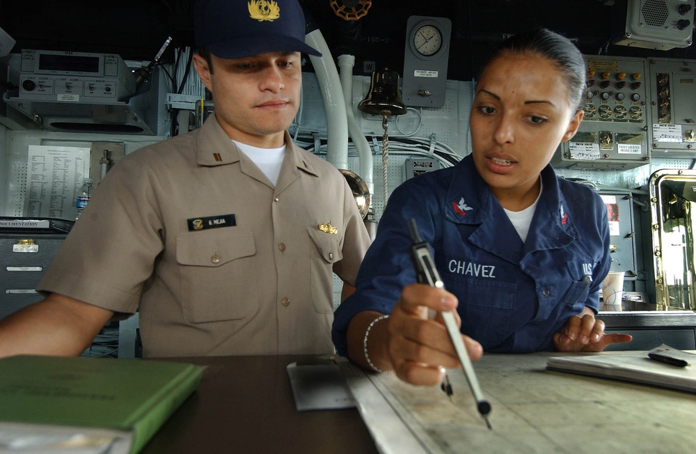 U.S. Navy Petty Officer 2nd Class Aurora Chavez explains the plotting of the position of the USS Thomas S. Gates.