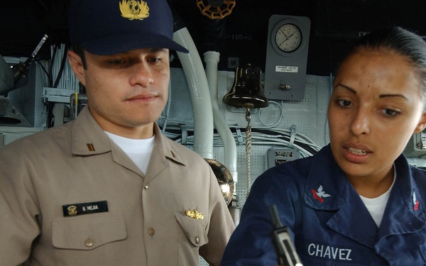 U.S. Navy Petty Officer 2nd Class Aurora Chavez explains the plotting of the position of the USS Thomas S. Gates.