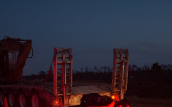 A Military Policeman places flares in the road.