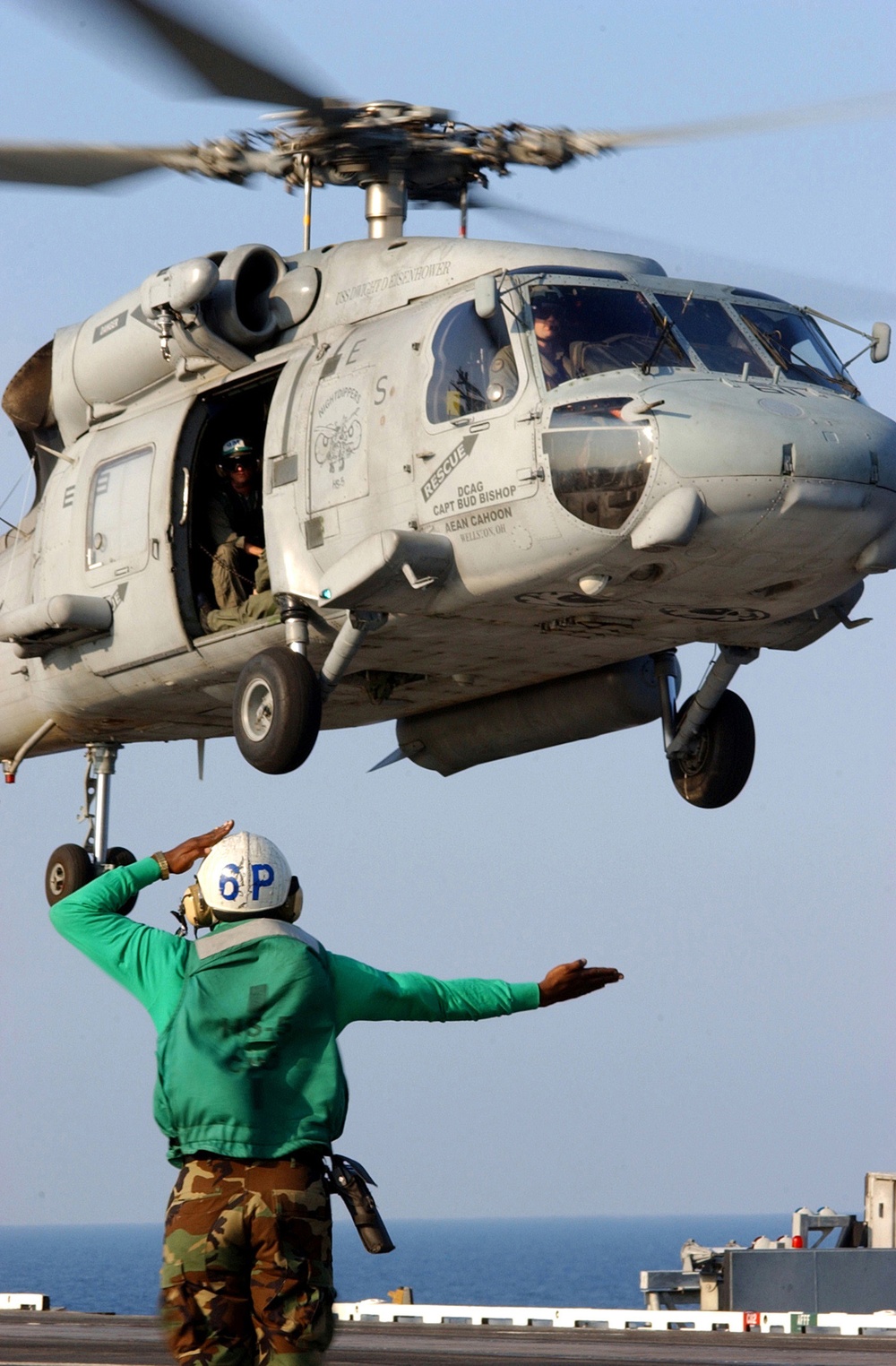 A U.S. Navy landing signal enlisted sends off an SH-60 Seahawk helicopter.