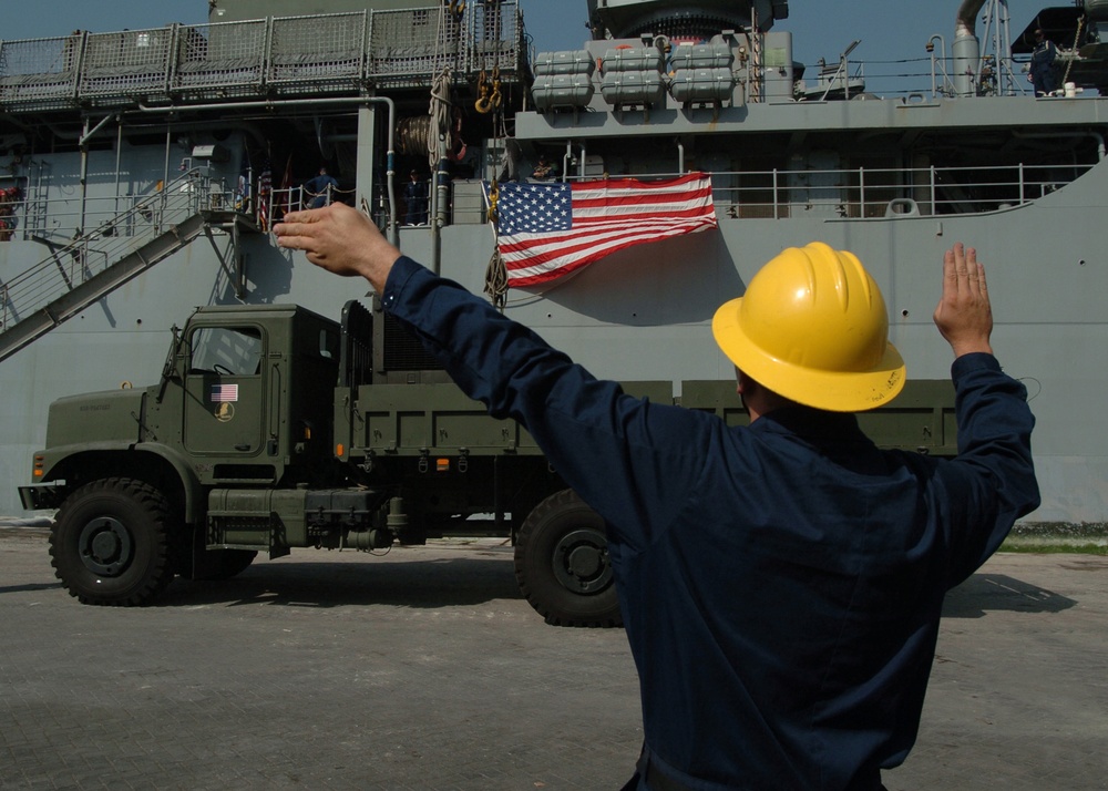 Navy Petty Officer 2nd Class Galen Roberts directs the operator of a crane. Navy Petty Officer 2nd Class Galen Roberts directs the operator of a crane.