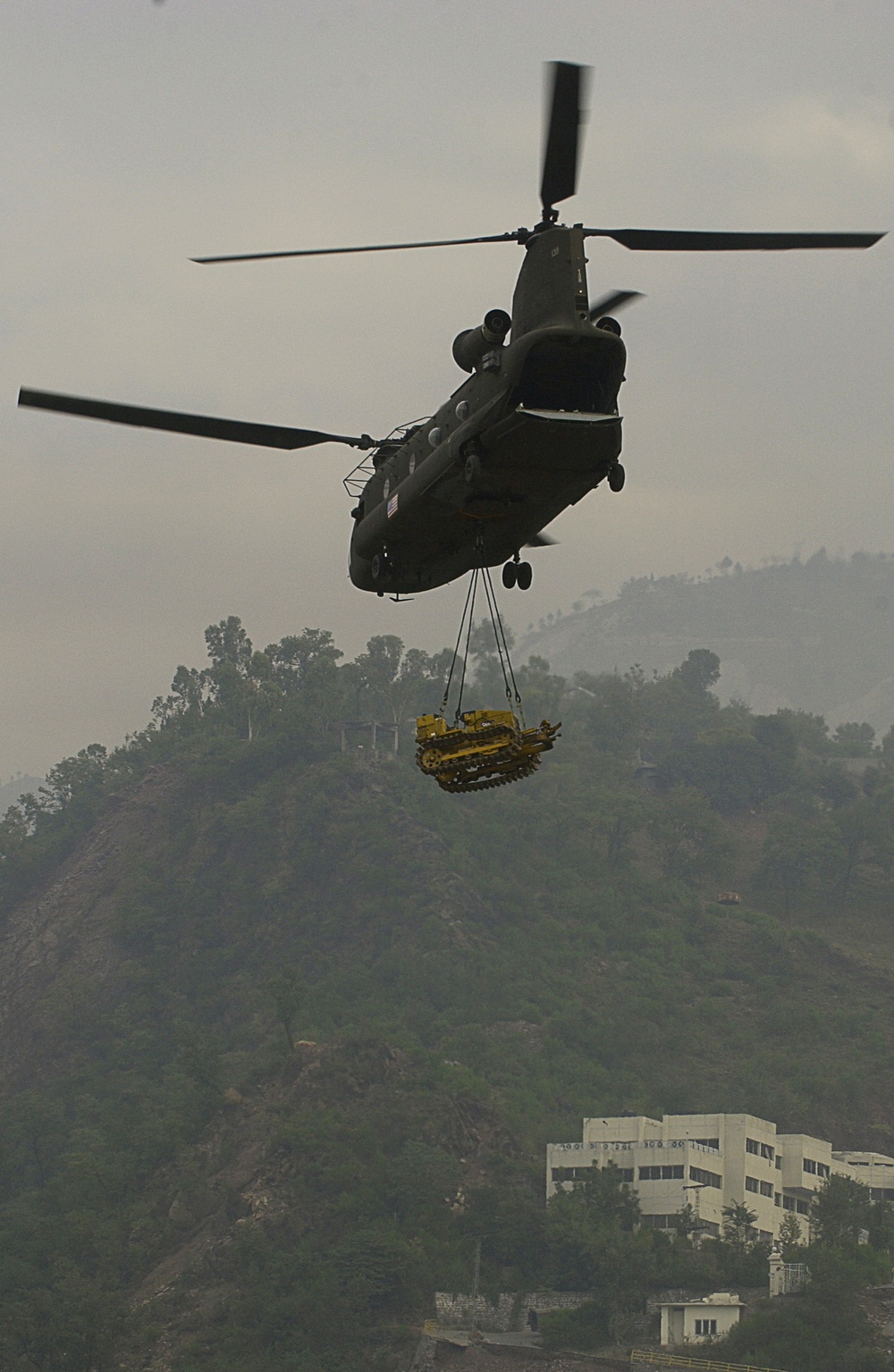 A U.S. Army CH-47D Chinook helicopter sling loads a bulldozer from Muzaffarabad, Pakistan.