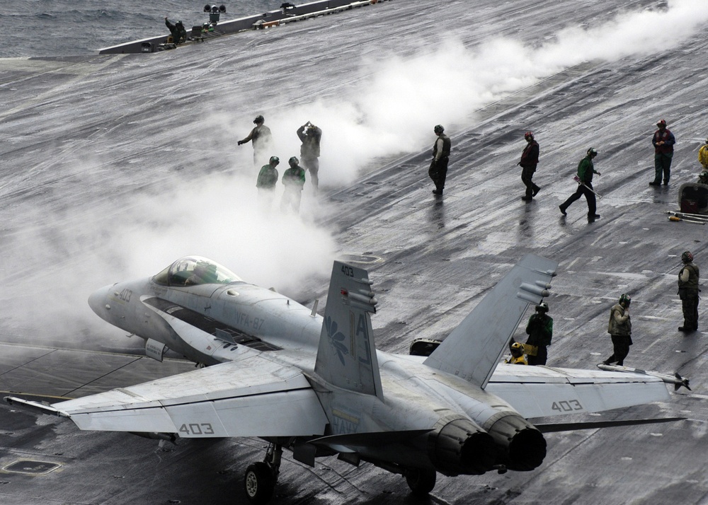 A Navy F/A-18C Hornet taxies to a steam-powered catapult.