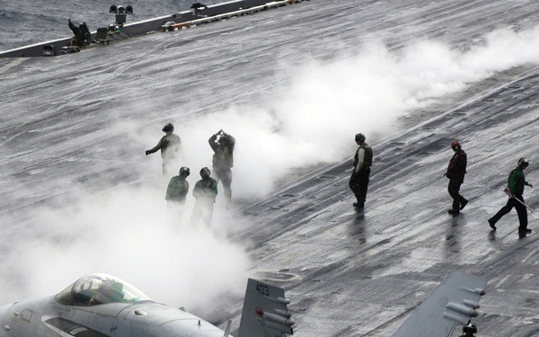 A Navy F/A-18C Hornet taxies to a steam-powered catapult.