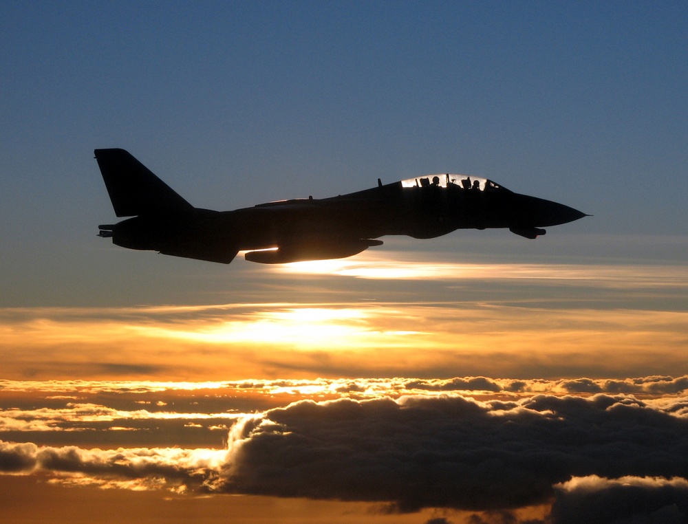 A Navy F-14D Tomcat is silhouetted against the sun as it flies a mission.