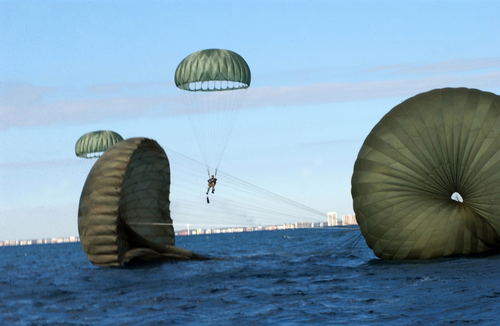 A Navy SEAL tries to steer clear of surrounding parachutes as he parachutes into the Gulf of Mexico.