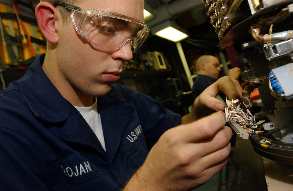 U.S. Navy Airman Marty Trojan replaces a connector on an infrared receiver.