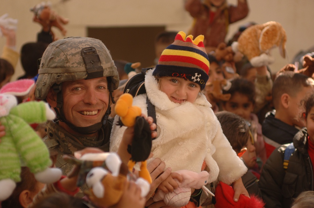 Staff Sgt. Richard Long holds up a little Iraqi girl with a new coat.