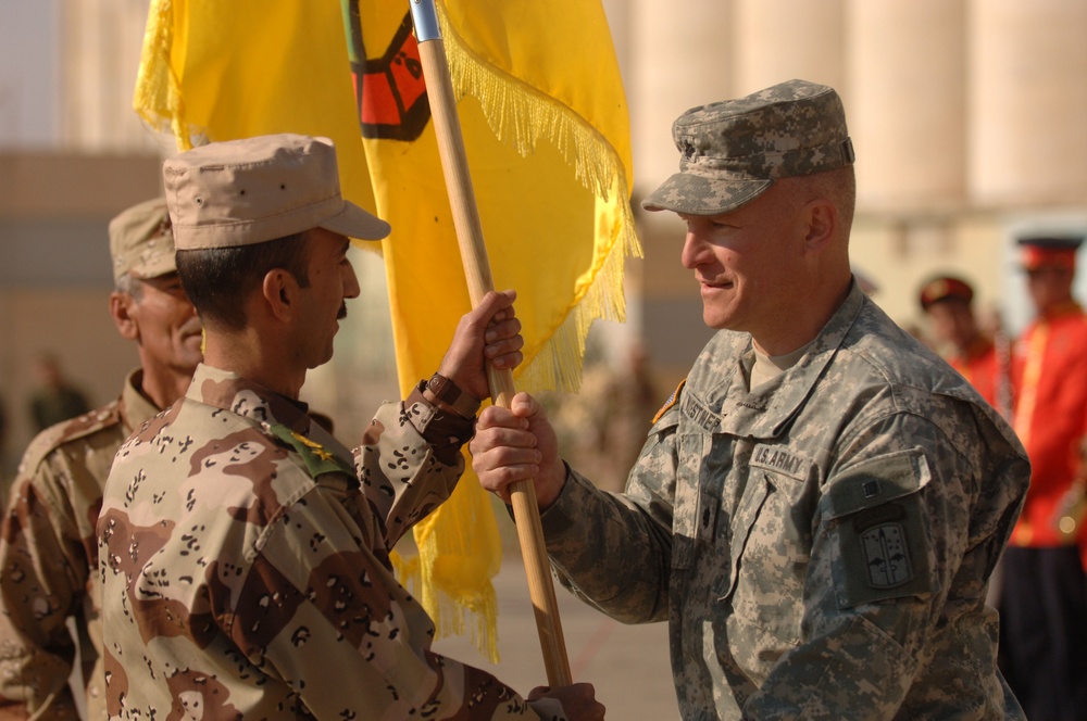 Lt. Col. Scott Wuestner passes the colors to Iraqi Lt. Col. Salahaddin Abdul Somad Hogar.