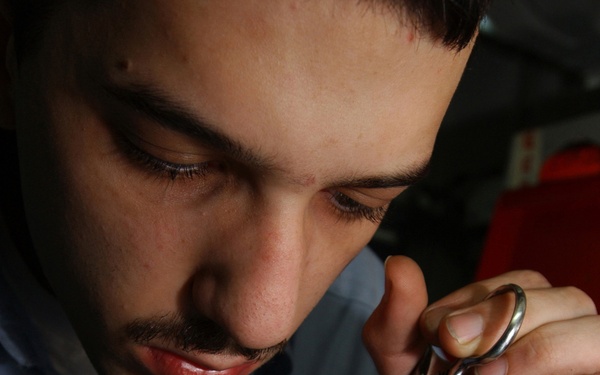 Petty Officer 3rd Class Stephen Hanna performs corrective maintenance on a portable radio communicator.