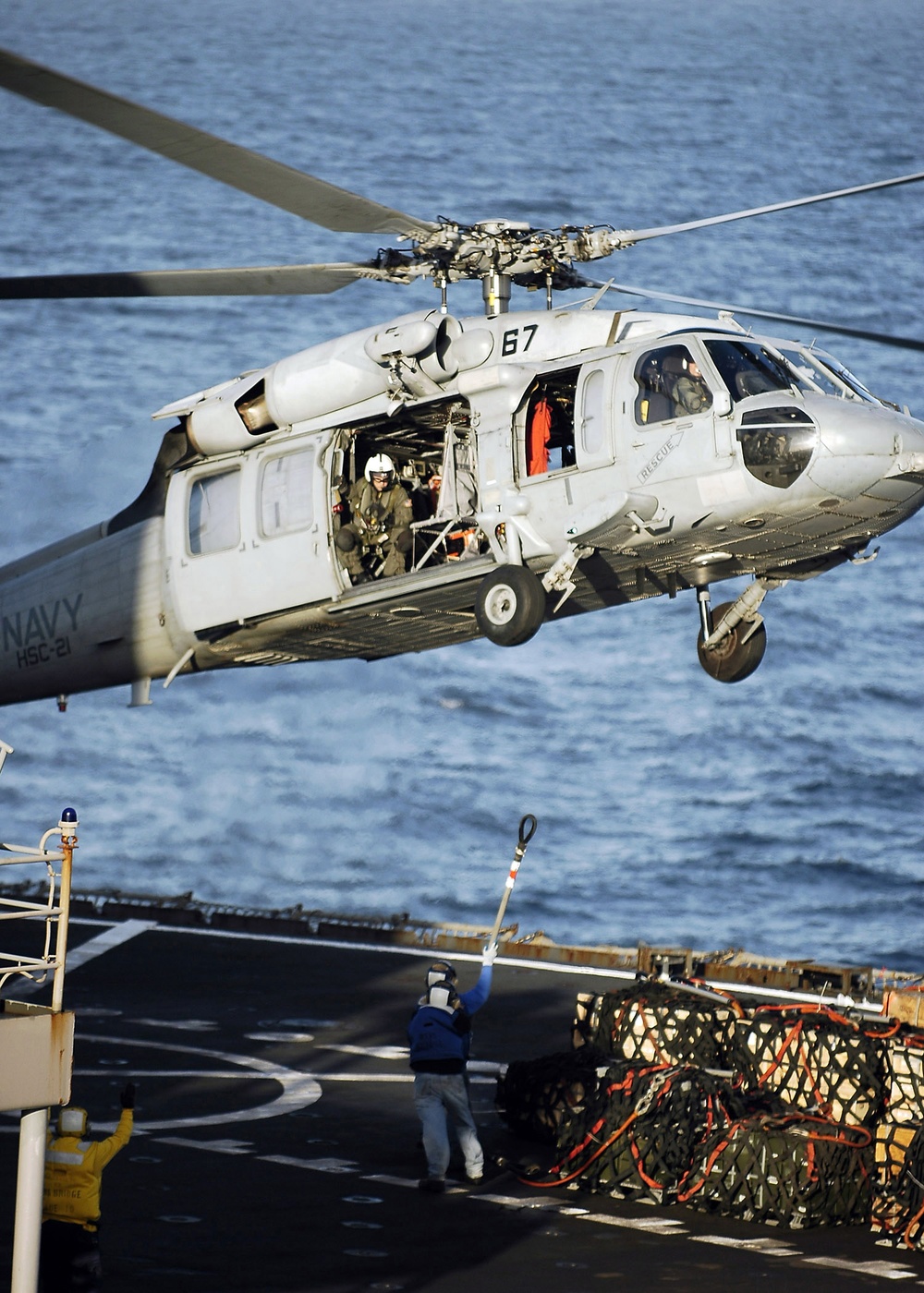 An SH-60 Seahawk helicopter prepares to pick up a cargo net.