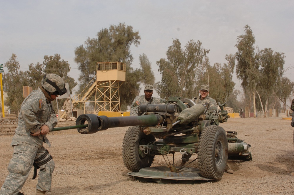 Pfc. Christian Zelaya pushes a cleaning rod down the barrel of a towed howitzer.