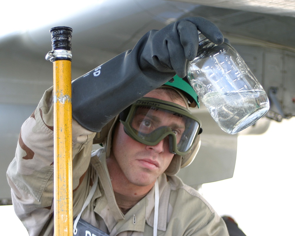 Petty Officer 2nd Class Graham Keithley looks at fuel drawn from a P-3C Orion aircraft.