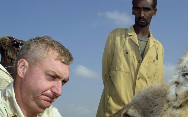 U.S. Army Veterinarian Maj. Jim Riche examines a donkey as its owner watches.