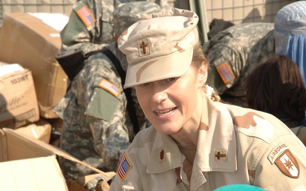 U.S. Army Chaplain Maj. Julie Rowan guides a young Afghan girl through a line.