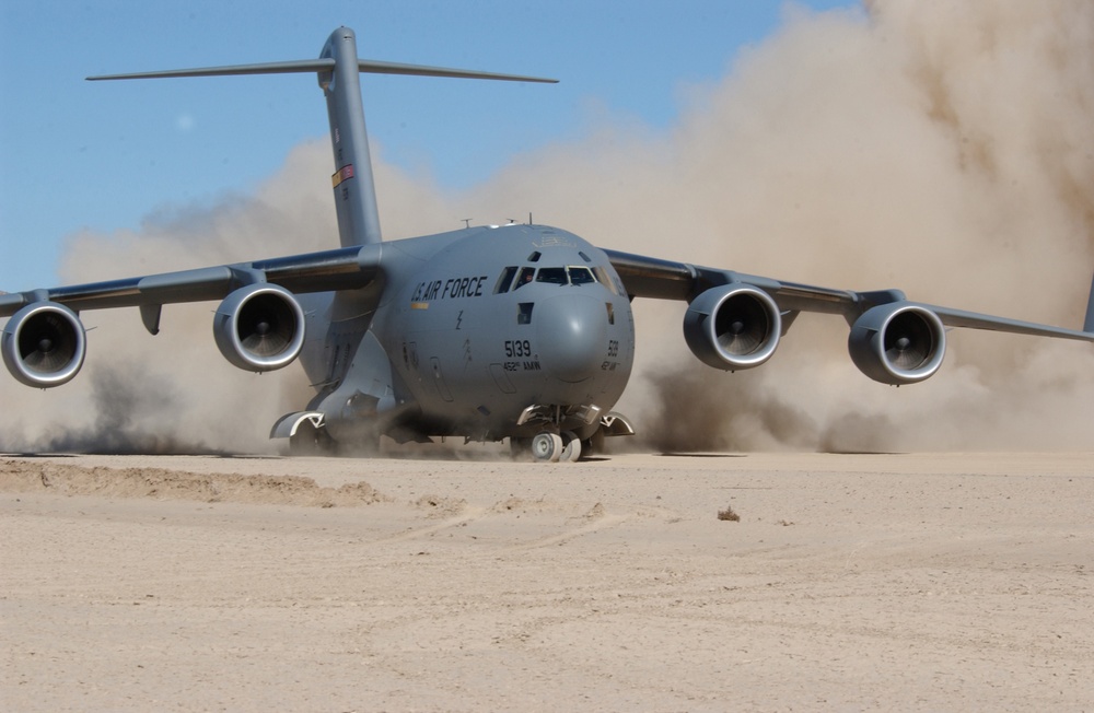 The jet engines of an Air Force C-17 Globemaster III kick up clouds of dust.
