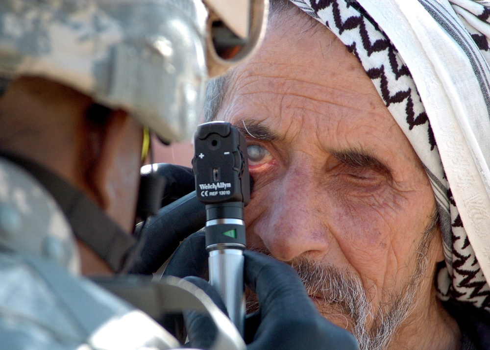 U.S. Army Capt. Edward Barnes examines an Iraqi man's eyes.