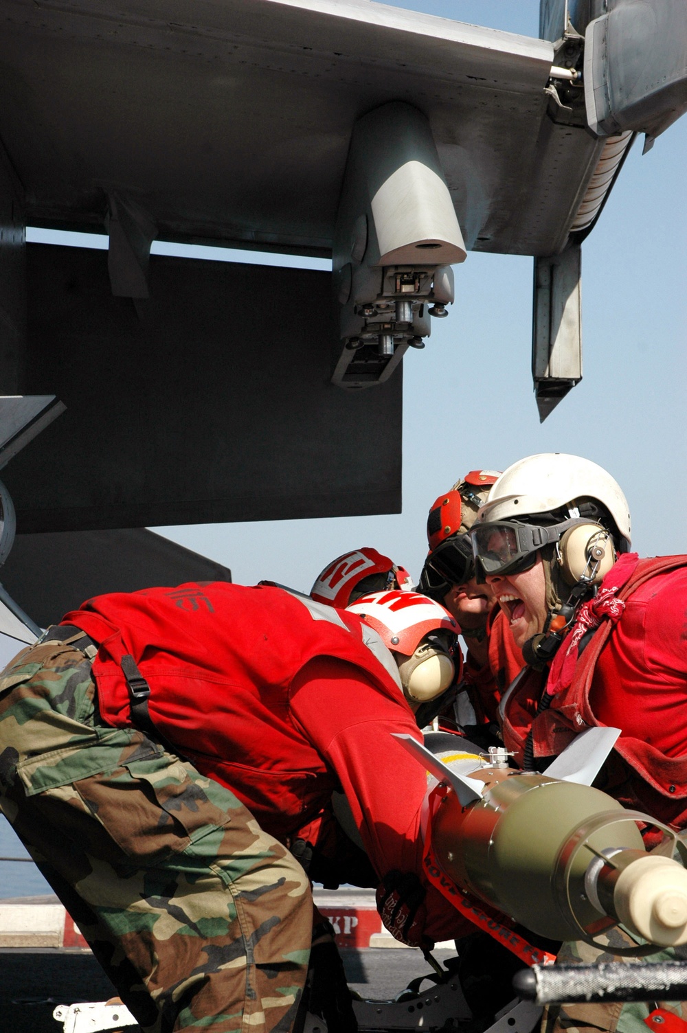U.S. Navy aviation ordnancemen lift a laser-guided bomb.