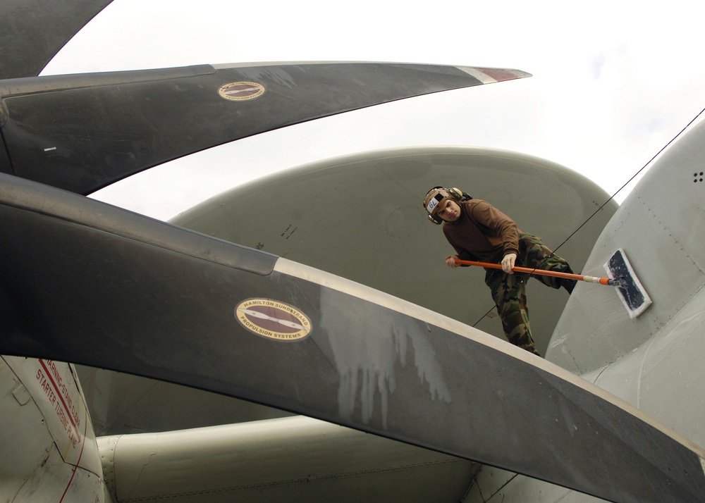 A U.S. Navy airman scrubs the fuselage of an E-2C Hawkeye.