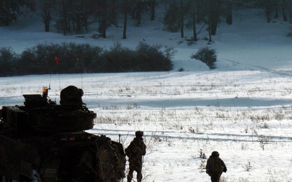 Soldiers wade through the snow after exiting a M2A2 ODS Bradley Fighting Vehicle.
