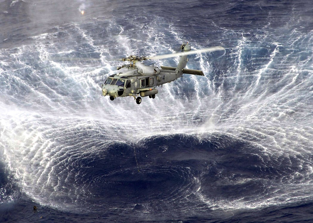 The rotor wash of a Navy SH-60F Seahawk helicopter kicks up a circle of spray in the Pacific Ocean.