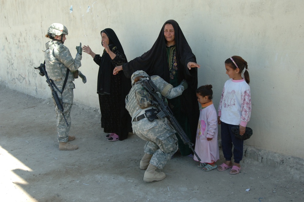 Two female U.S. Army soldiers search two Iraqi women.