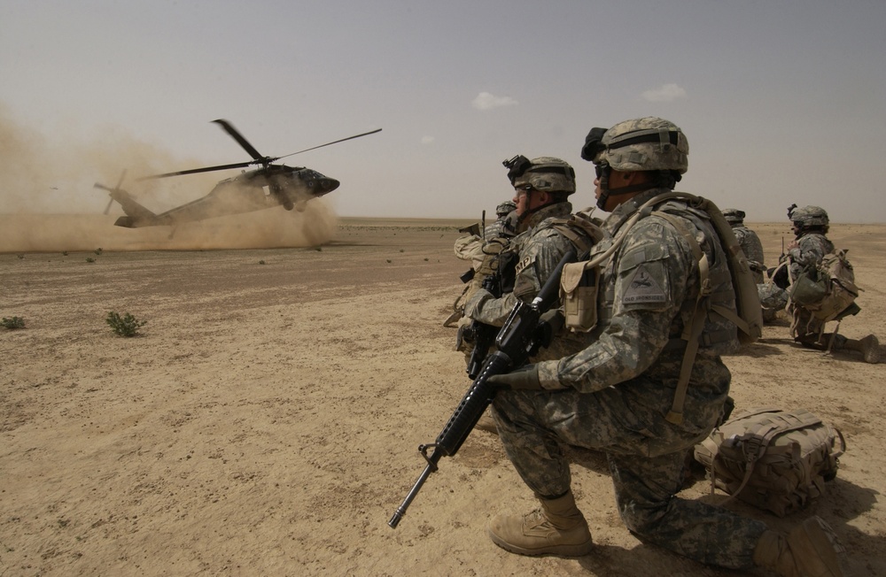 U.S. Army soldiers wait to board a UH-60 Black Hawk helicopter.
