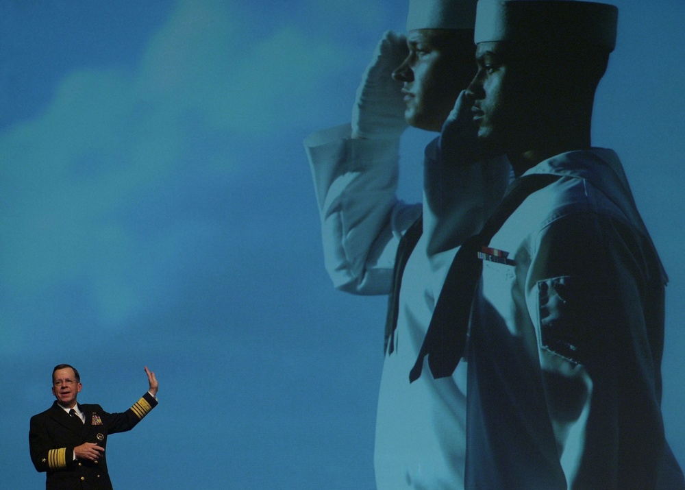 Artwork of two sailors towers over Adm. Mike Mullen as he speaks.