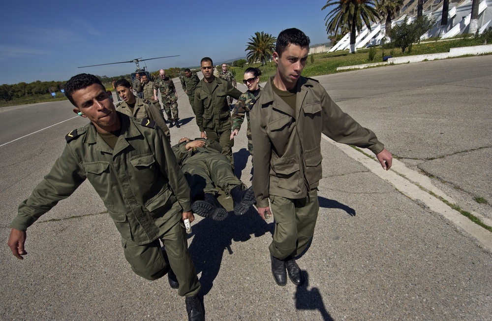 Tunisian military medical nurses carry a stretcher from a Tunisian helicopter.
