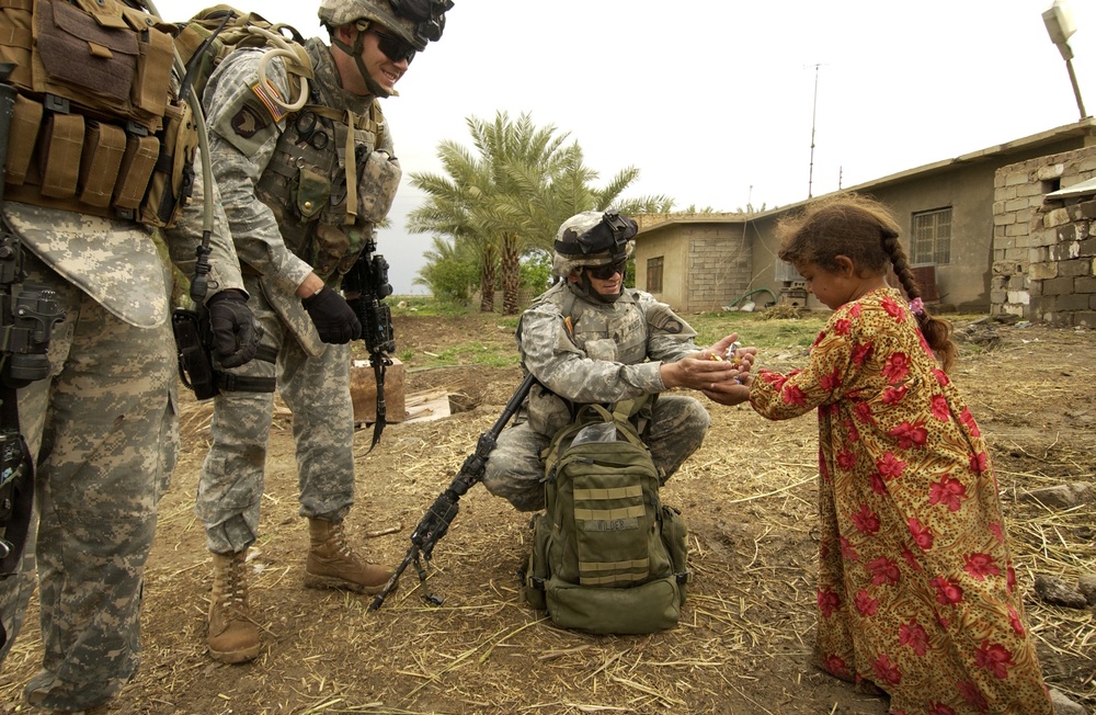 Army 1st Sgt. William Wilder gives a handful of candy to an Iraqi girl.