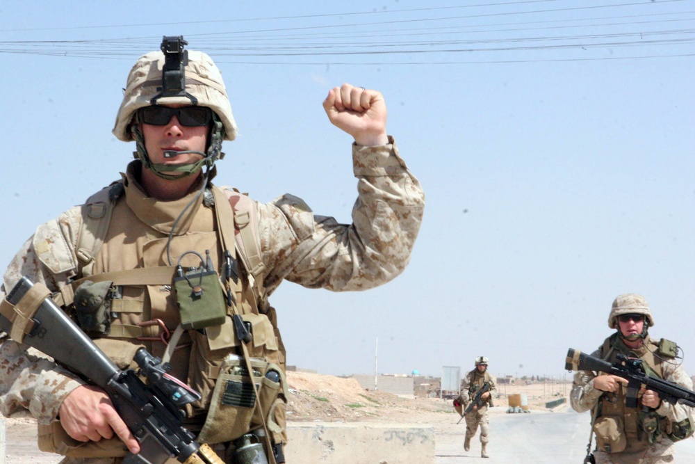 U.S. Marine Corps Cpl. Adam A. Anderson signals to his squad to halt.