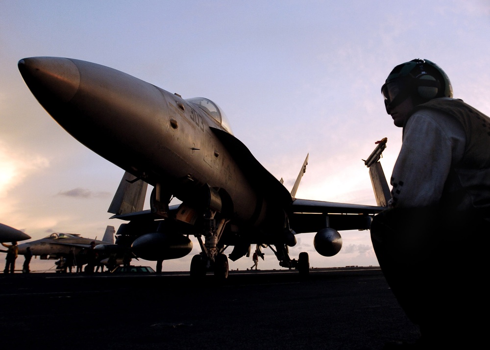A U.S. Navy flight deck crewman watches as an F/A-18C Hornet aircraft.