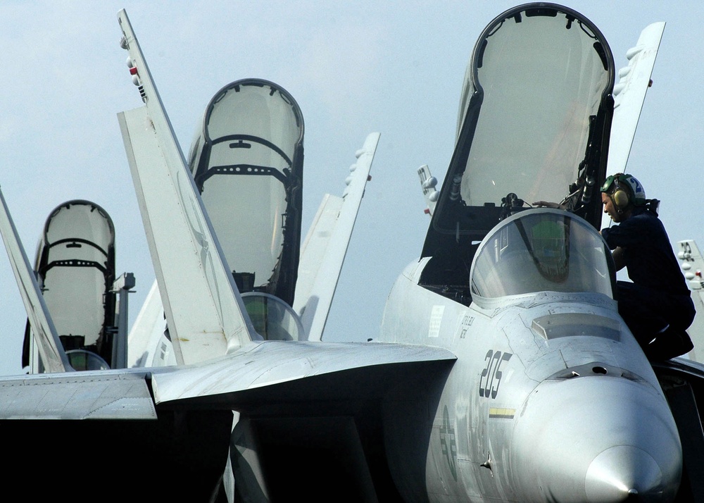 Airman Jason Rickards adjusts some equipment in the cockpit of an F/A-18E Super Hornet.