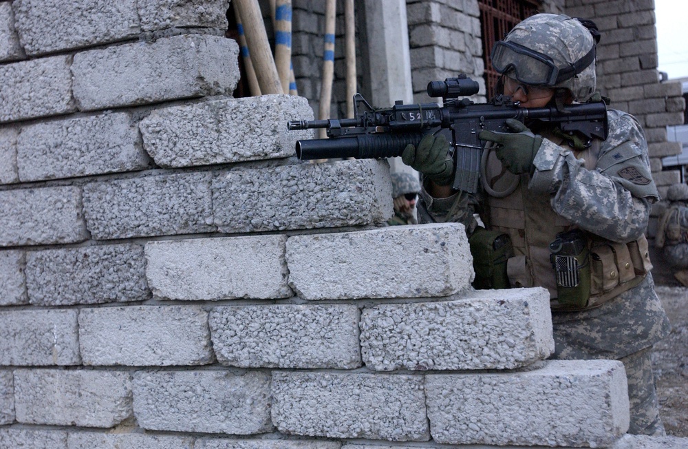 Army Pfc. Douglas Dalton uses his optical sights to scan down the street.